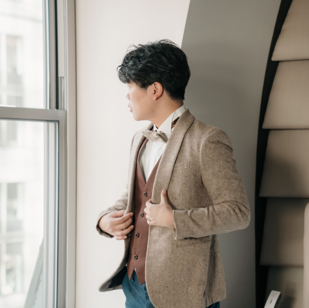 男性がスーツ姿で窓の外を見ている